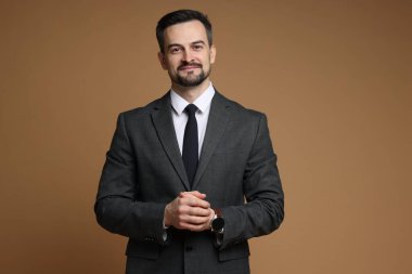 Kahverengi arka planda klasik takım elbiseli yakışıklı bir adam.