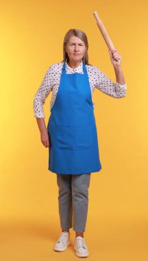 Sarı arka planda merdanesi olan kızgın kadın.