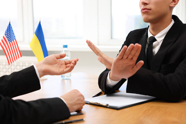 Diplomats negotiating during meeting at wooden table indoors, closeup