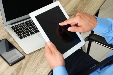 Tabletli, akıllı telefonlu ve bilgisayarlı bir iş adamı ahşap masada, yakın plan. Modern teknoloji