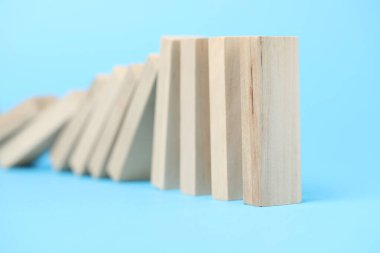 Domino etkisi. Tahta bloklar açık mavi arkaplan üzerine düşüyor, yakın plan