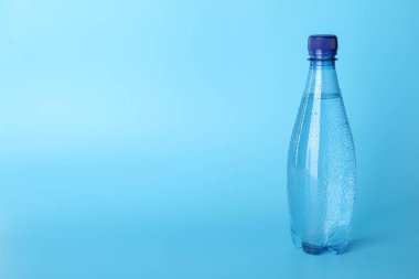 Açık mavi arka planda plastik su şişesi. Metin için boşluk