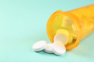 Sarı arka planda antibiyotik hapları olan bir ilaç şişesi, yakın plan. Metin için boşluk