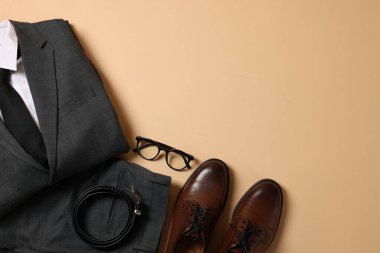 Zarif erkek kıyafeti. Şık takım elbise, aksesuarlar ve bej arka planda ayakkabılar, düz yatak. Metin için boşluk