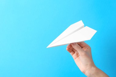 Açık mavi arka planda el yapımı kağıt uçaklı bir kadın, yakın plan. Metin için boşluk