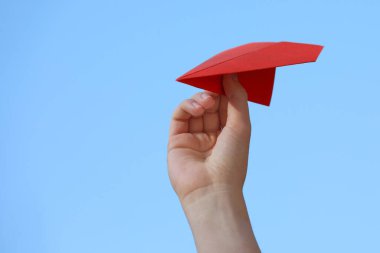 El yapımı kağıt uçakla açık havada gökyüzüne karşı duran kadın, yakın plan.