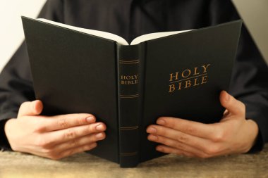 Kutsal İncil 'i ahşap masada okuyan kadın, yakın plan.