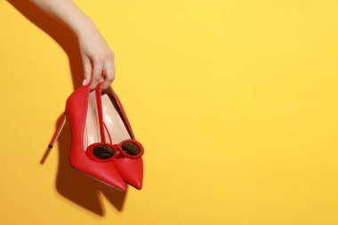 Turuncu arka planda güzel güneş gözlüklü ve ayakkabılı bir kadın, yakın plan. Metin için boşluk