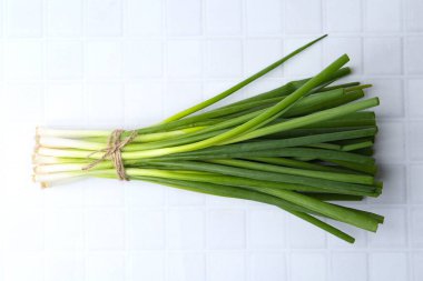 Beyaz fayanslı masada taze taze soğan var.