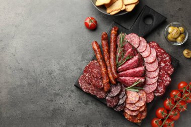 Gri masada servis edilen farklı tütsülenmiş sosisler. Metin için boşluk