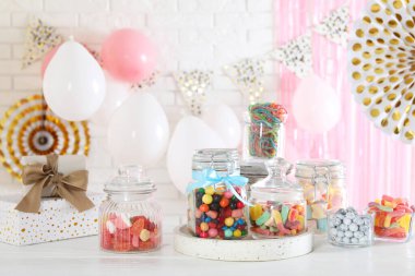 Candy bar. Many different sweets on white wooden table in festive decorated room clipart