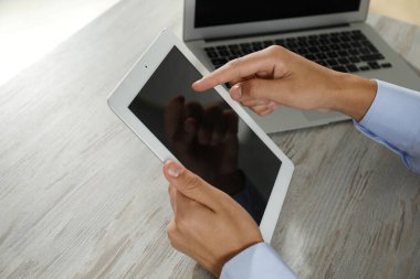 Tabletli ve laptoplu bir iş adamı ahşap masada, yakın plan. Modern teknoloji