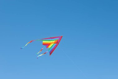 Mavi gökyüzünde uçan renkli bir uçurtma