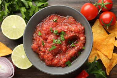 Lezzetli baharatlı salsa sosu kasede ve ahşap masada ürünler.