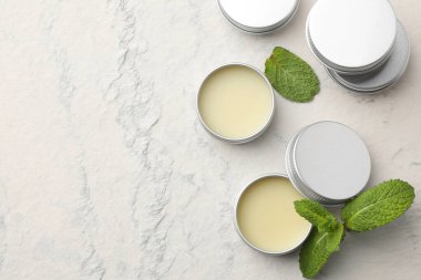 Mint lip balms and green leaves on beige textured background, flat lay. Space for text clipart