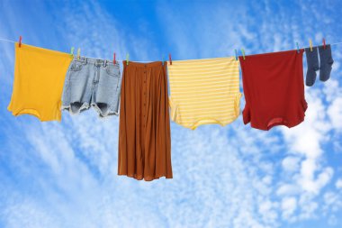 Different clothes drying on washing line against blue sky