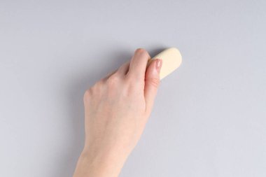 Gri arkaplanda silgi kullanan kadın, yakın plan