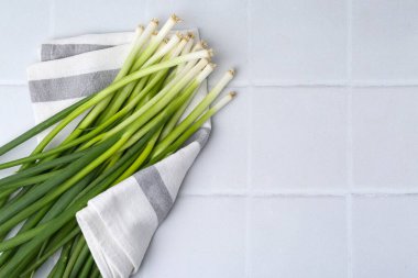 Beyaz fayanslı masada taze yeşil soğan, üst manzara. Metin için boşluk