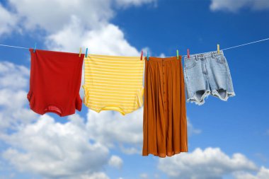 Different clothes drying on washing line against blue sky