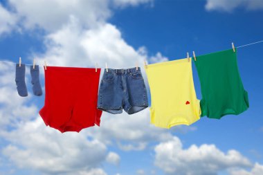 Different clothes drying on washing line against blue sky