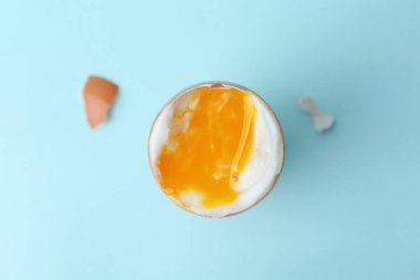 Açık mavi arka planda, yumurta kabında kaynamış yumurta, üst manzara.