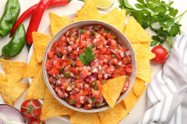 Tabakta nefis salsa, malzemeler ve bej masada nacho cipsi.