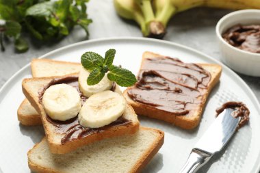 Çikolata yağlı sandviçler, muzlar, nane ve bıçak masada, yakın plan.