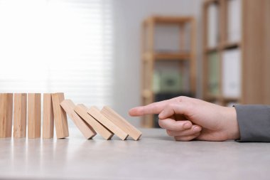 Domino etkisi. Masada tahta blokları iten kadın, yakın plan.