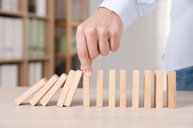 Ahşap blokların masada düşmesini engelleyen adam, yakın plan. Domino etkisi
