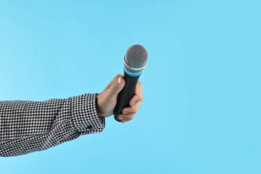 Açık mavi arka planda mikrofonu olan adam, yakın plan.