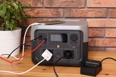 İçerideki ahşap masada taşınabilir elektrik santralinden şarj edilen cihazlar