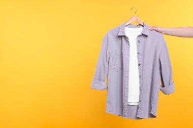 Sarı arka planda elbise askısı olan bir kadın, yakın plan. Metin için boşluk