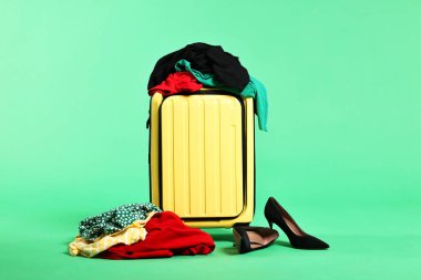 Bavul, dağınık kıyafetler ve yeşil arka planda ayakkabılar.