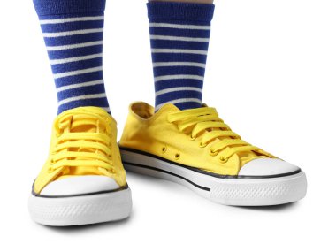 Beyaz arka planda büyük boy sarı spor ayakkabı giyen çocuk, yakın plan.