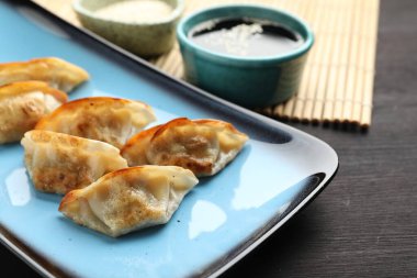 Kızarmış gyoza köftesi ve soya sosu ahşap masada, yakın plan.