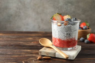 Çilekli lezzetli chia pudingi, yaban mersini ve bademler ahşap masada, metin için yer var.