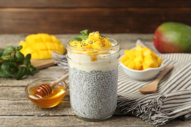 Bardakta mangolu lezzetli chia pudingi ve ahşap masada bal.