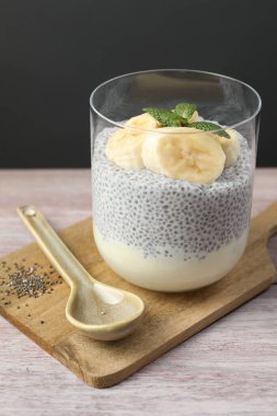 Muz ve nane aromalı lezzetli chia pudingi. Ahşap masada servis ediliyor. Gri arka planda, yakın plan.
