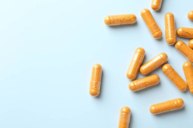 Açık mavi arkaplandaki zerdeçal kapsülleri düz. Metin için boşluk