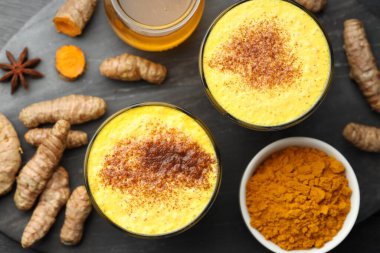 Lezzetli zerdeçal latte, pudra ve rizom siyah ahşap masa, düz yatar