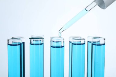 Beyaz arka planda test tüplerine sıvı damlatılıyor