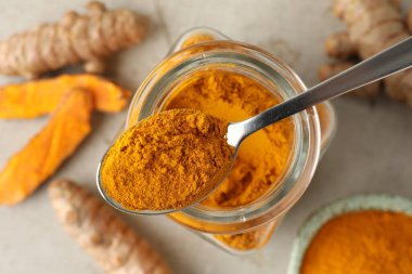 Masadaki cam kavanozdan kaşıkla aromatik zerdeçal tozu alıyorum.