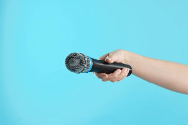 Açık mavi arka planda mikrofonu olan kadın, yakın plan.
