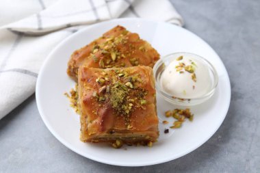 Lezzetli baklava, doğranmış fındık ve bir kepçe dondurma, yakın plan.