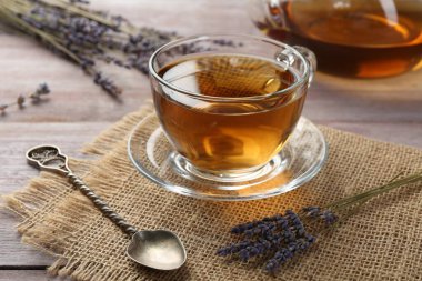 Cam bardakta Aromatik lavanta çayı, tahta masada kaşık ve kuru çiçekler, yakın plan
