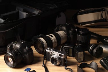 Profesyonel fotoğrafçının ekipmanı ve sırt çantası ahşap masada.