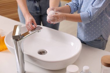 Anne ve kız ellerini lavabonun üstünde yıkıyor, kapalı.