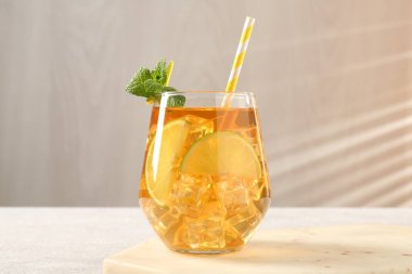 Buzlu çayı limon dilimleriyle, nane şekeriyle ve cam bardakta pipet içerek gri arka planda, yakın planda