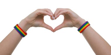 LGBT renginde bileklik takan ve beyaz arkaplanda kalp hareketi yapan bir kadın.