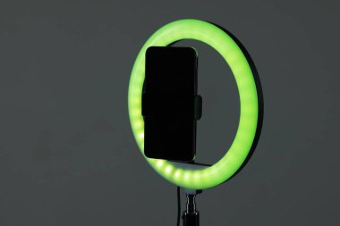 Gri arka planda akıllı telefonu olan halka lambası, yakın plan. Metin için boşluk